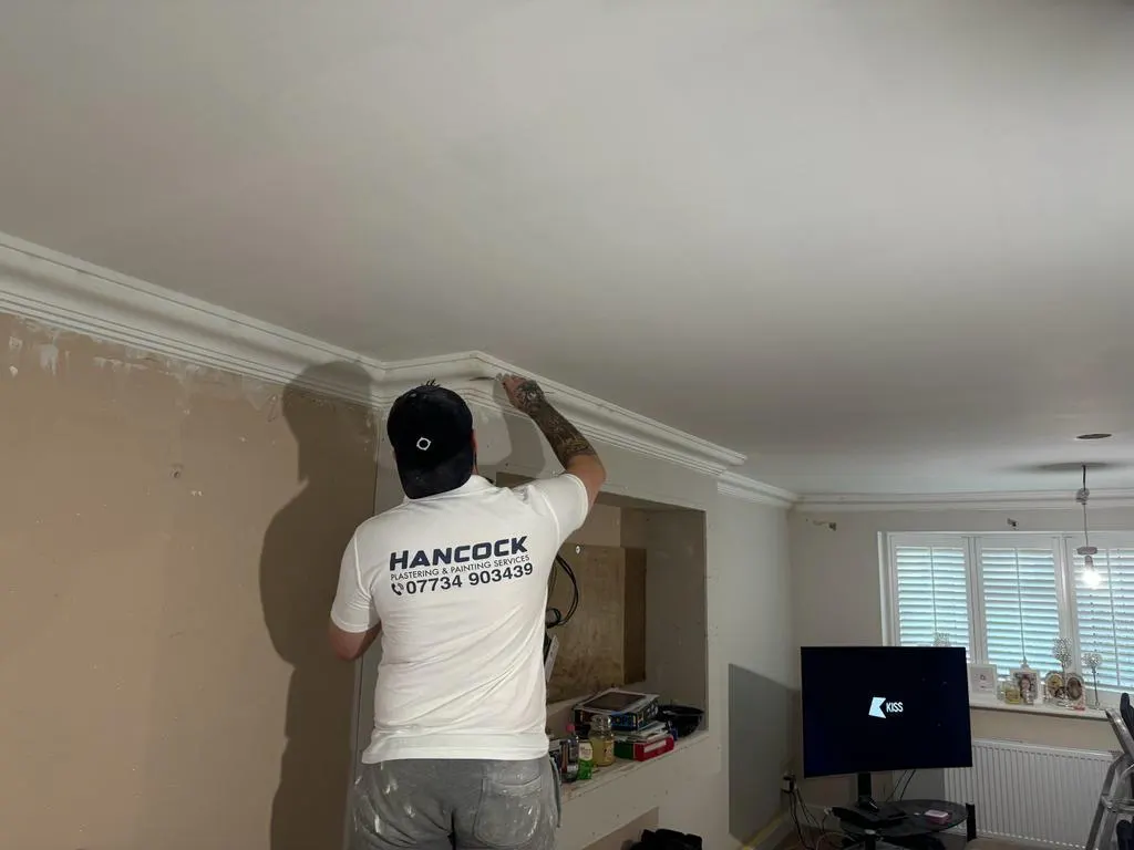 Hancock decorator cutting in fresh white paint along the cornice of a finished living room