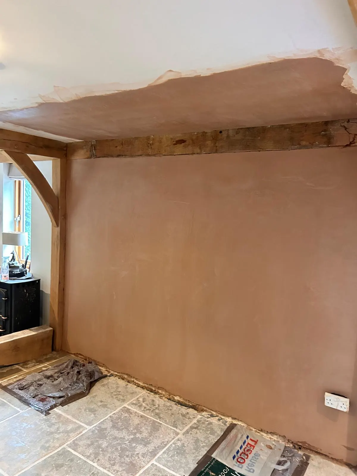 Freshly skimmed feature wall around an exposed oak beam in a period cottage