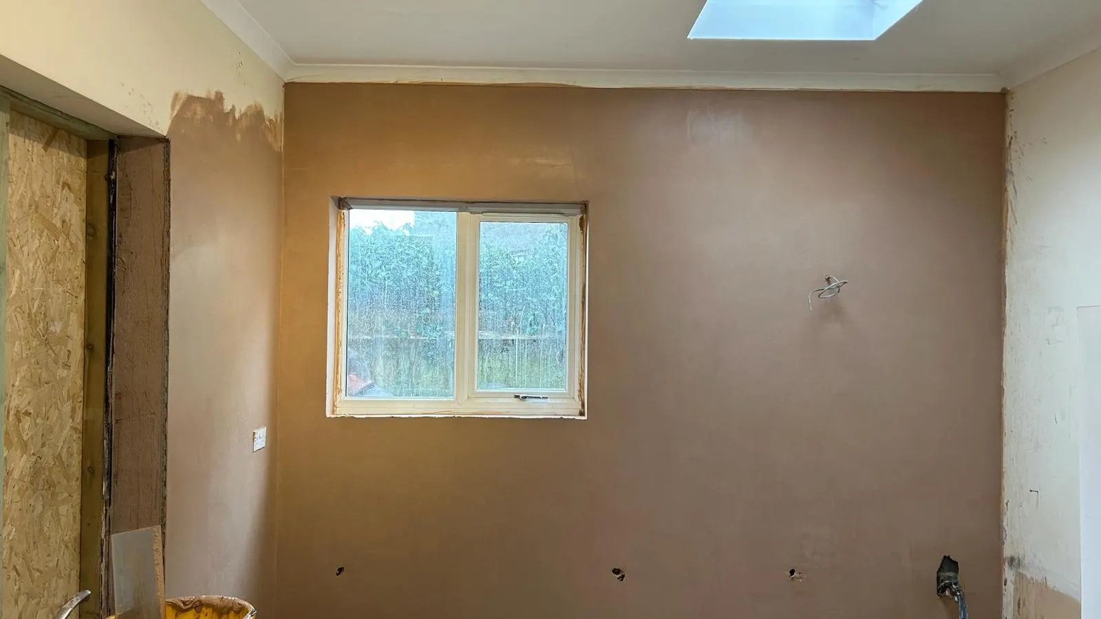 Newly plastered room with a smooth skim finish around the window and skylight