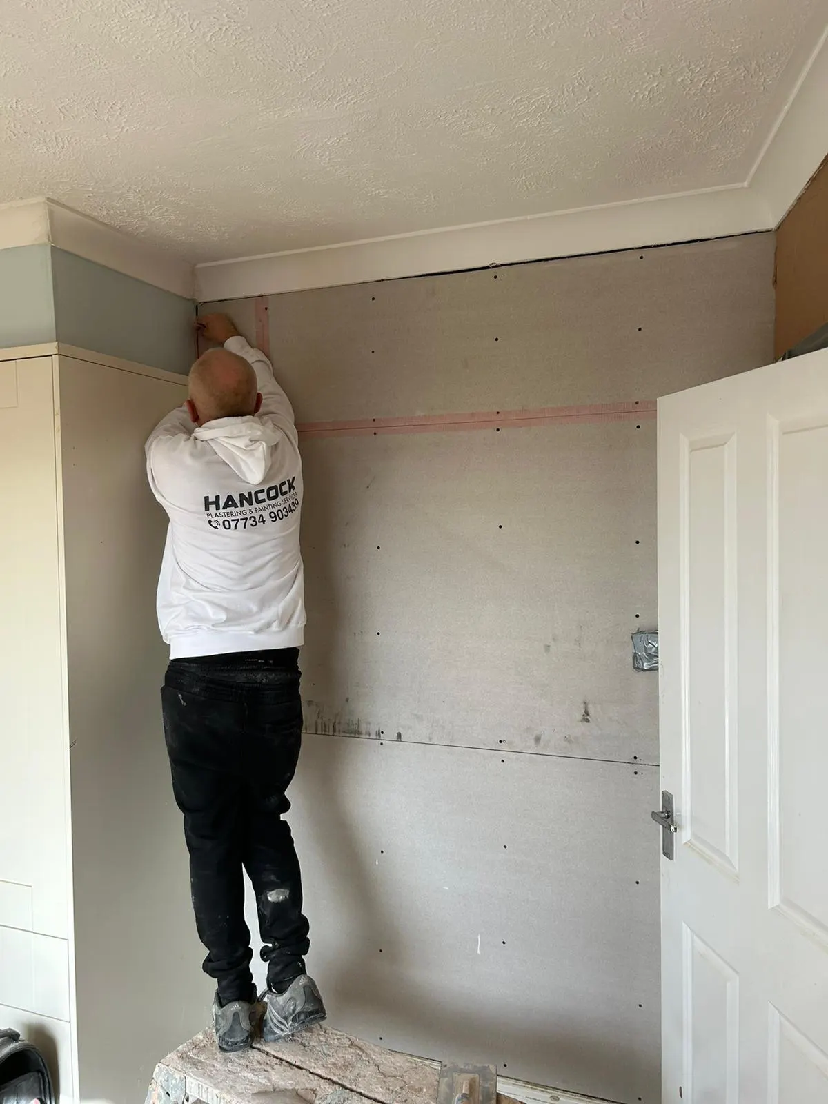 Hancock plasterer dry-lining and taping plasterboard in a corner