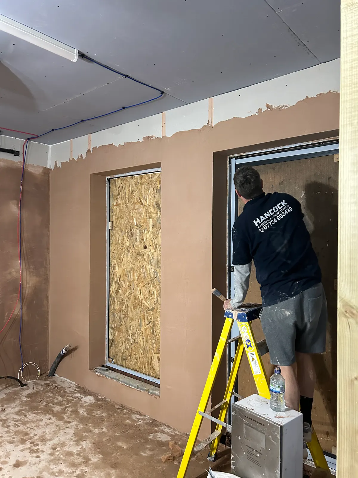 Hancock plasterer skimming an extension wall around a new window opening