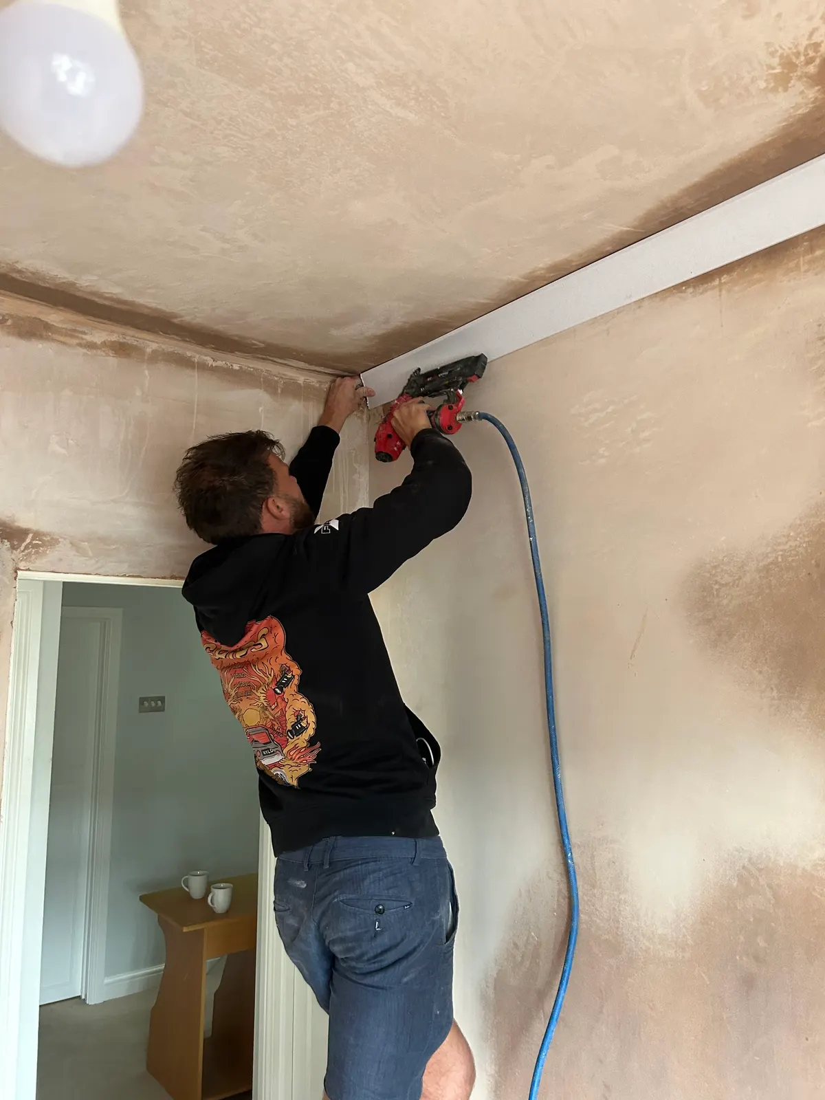 Hancock plasterer smoothing the join between a freshly skimmed wall and ceiling