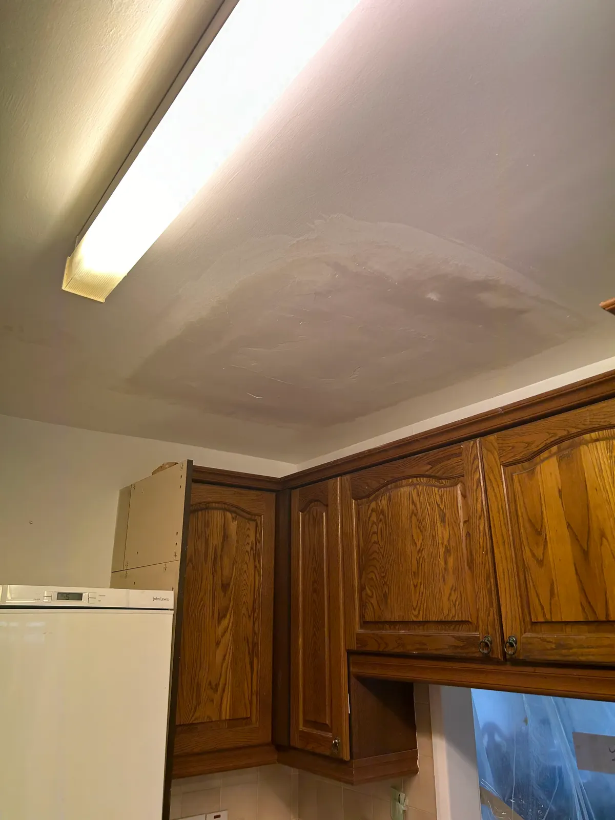 Repaired and re-skimmed kitchen ceiling above fitted oak units
